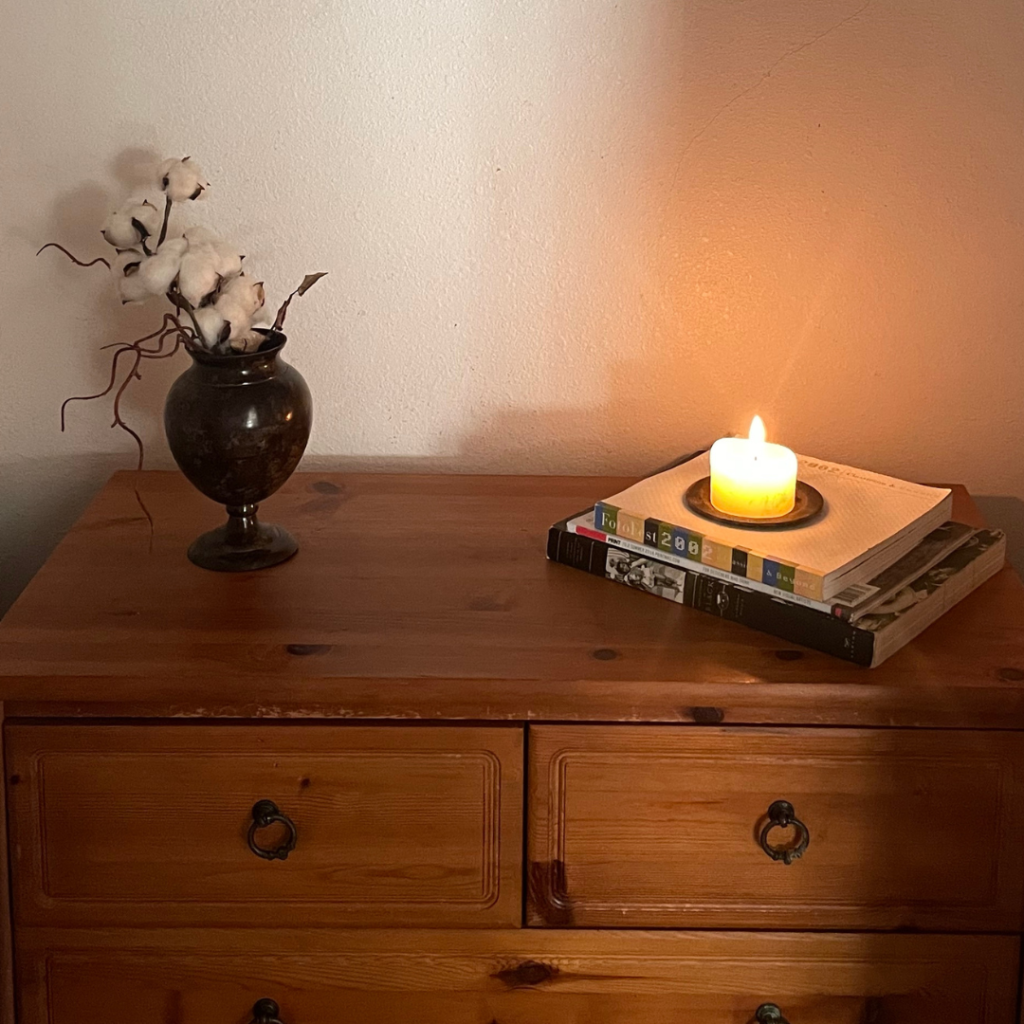Cotton stems arranged in a dark vase beside a lit candle in Lisa N. Alexanderโs Los Angeles home.