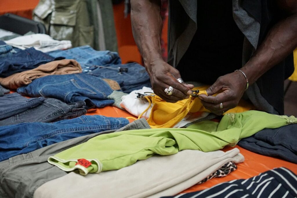A person examining a yellow garment among secondhand clothing at an upcycled store in Berlin.